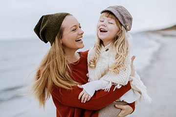 Woman carrying child on beach