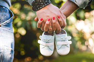 Couple holding hands and tiny shoes